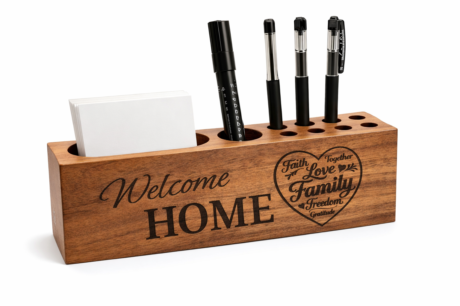 Wooden pen and pencil holder that is engraved with the words "Welcome Home" along with a heart design containing words like "Family", "Faith" and "Love".